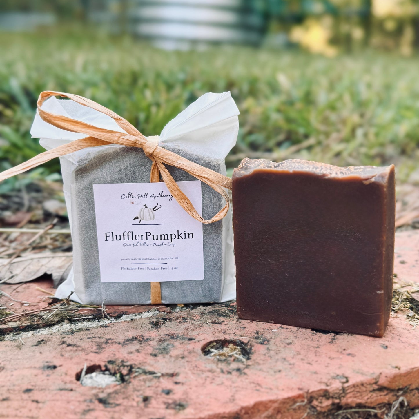 Bar of soap and wrapped product with 'FlufflerPumpkin' label on a natural background
