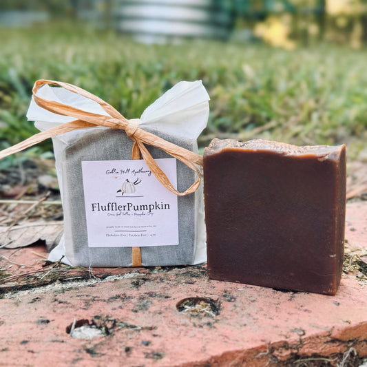 Bar of soap and wrapped product with 'FlufflerPumpkin' label on a natural background