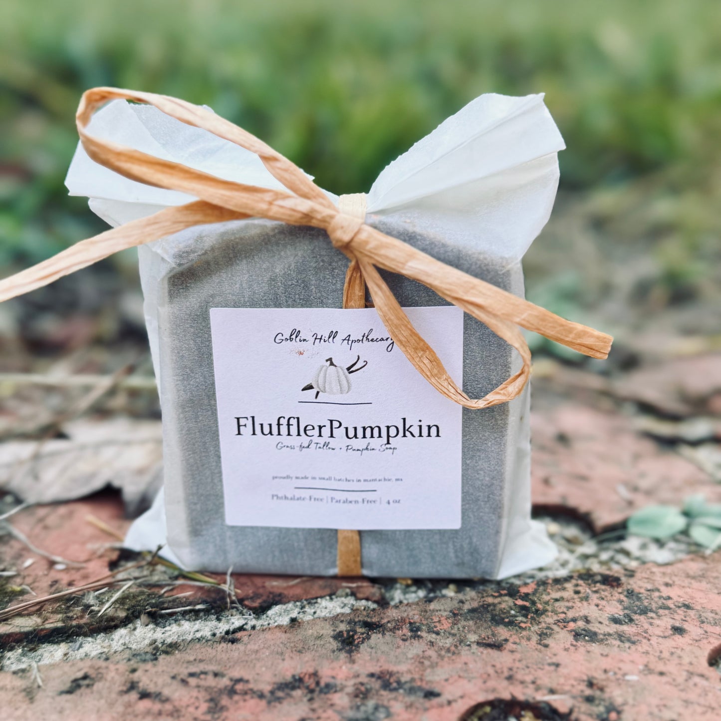 Gray package with a bow and 'FlufflerPumpkin' label on a natural background