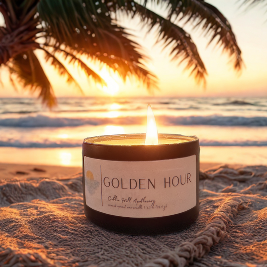 Candle labeled 'Golden Hour' on a beach with palm trees and sunset in the background