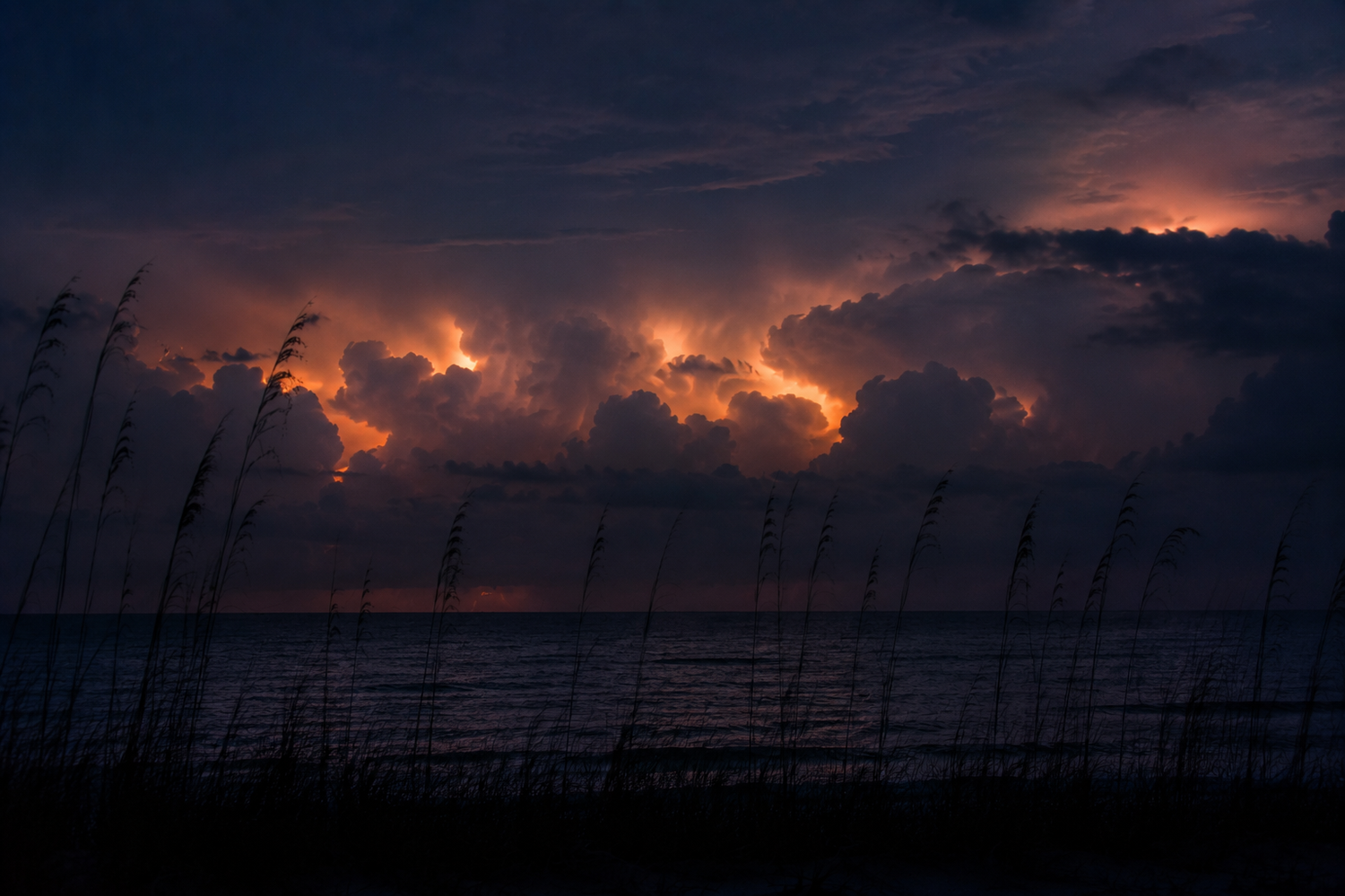 cloud-to-cloud lightning over calm seas at night