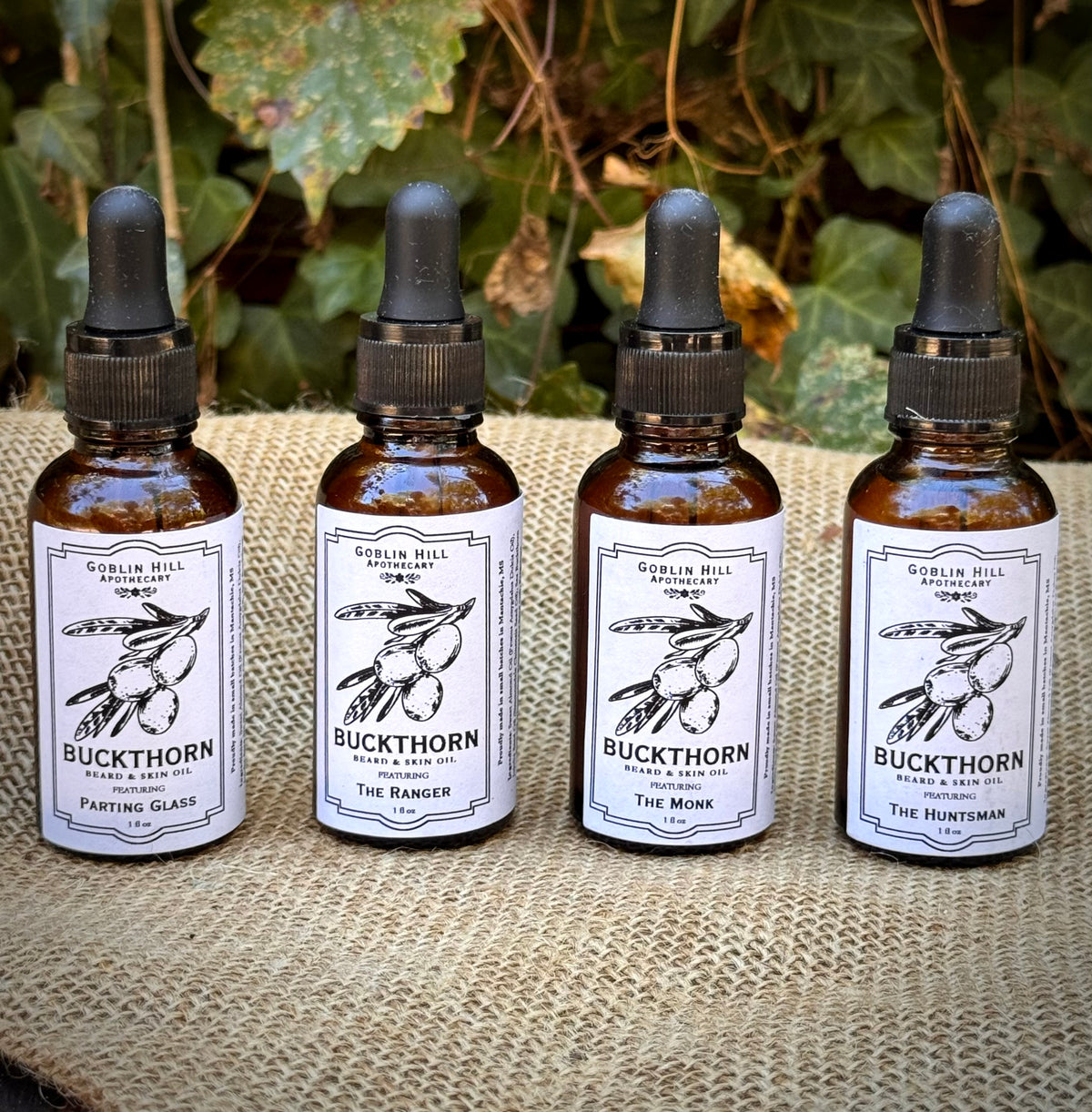 Four amber bottles of buckthorn beard oil sitting on a burlap background 