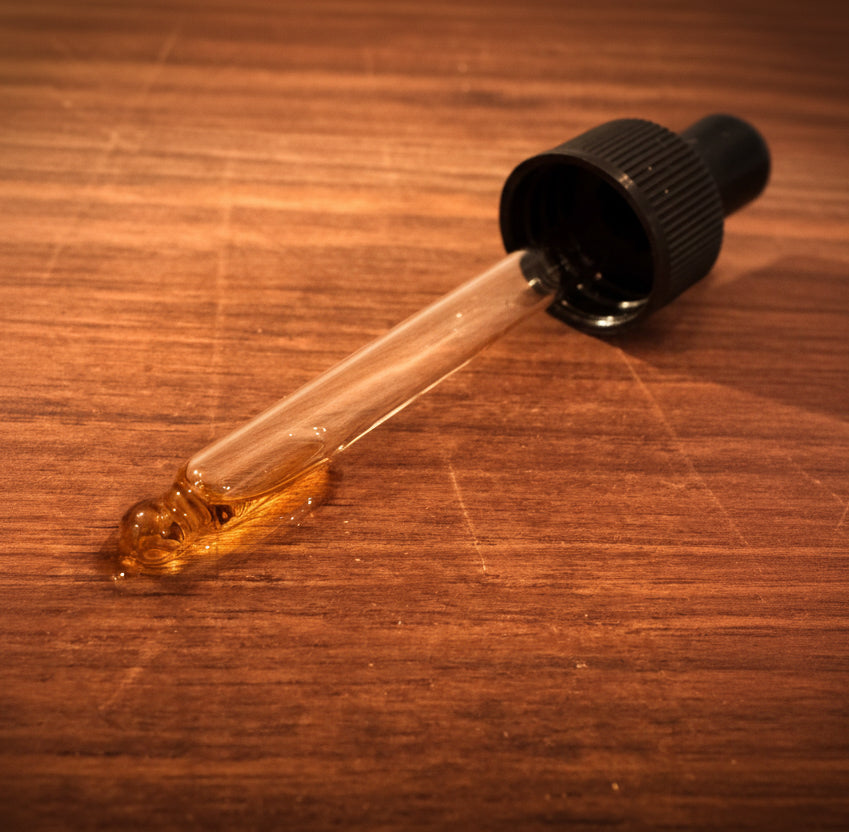 Dropper with brown liquid on a wooden surface