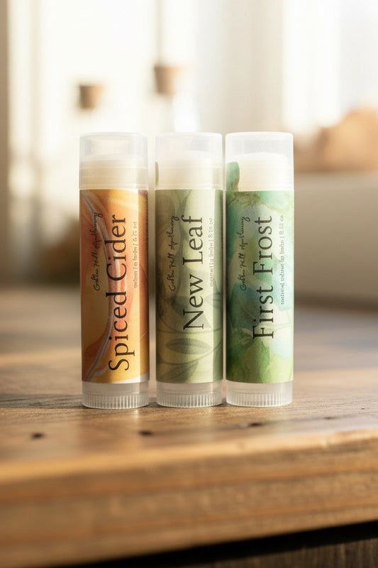 Three sticks of lip balm on a wooden counter
