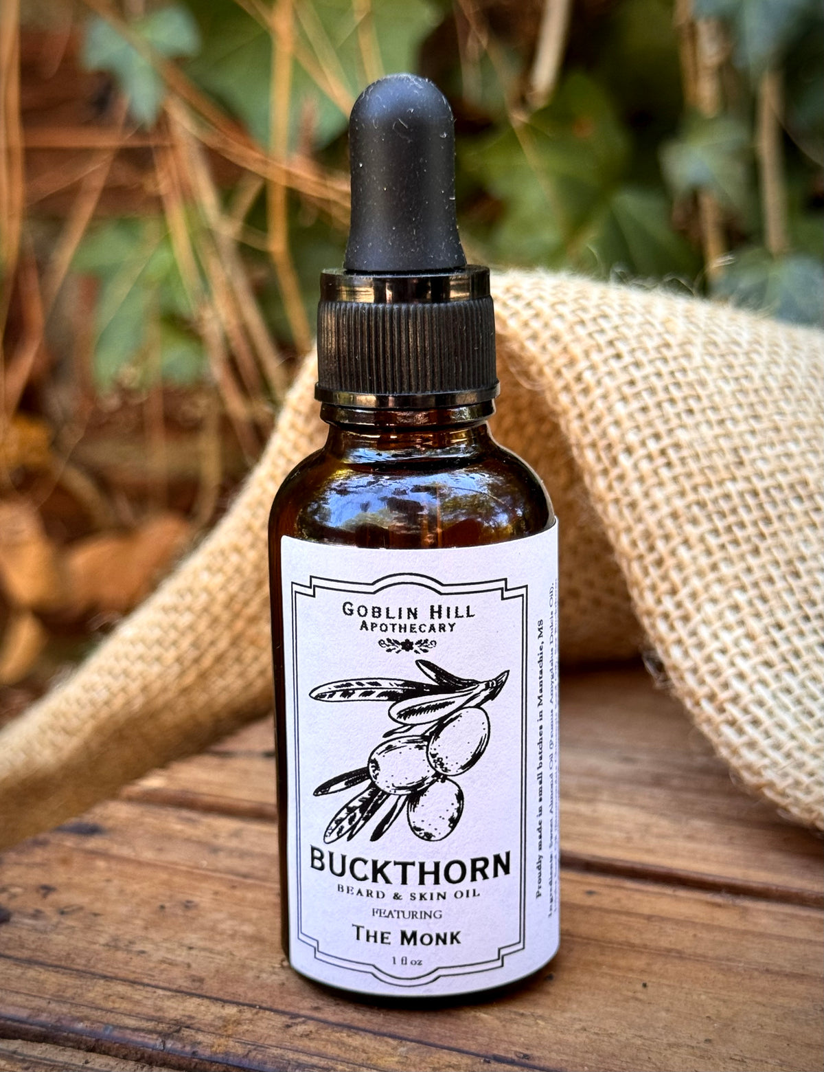 Amber dropper bottle of buckthorn beard oil on a wooden background 