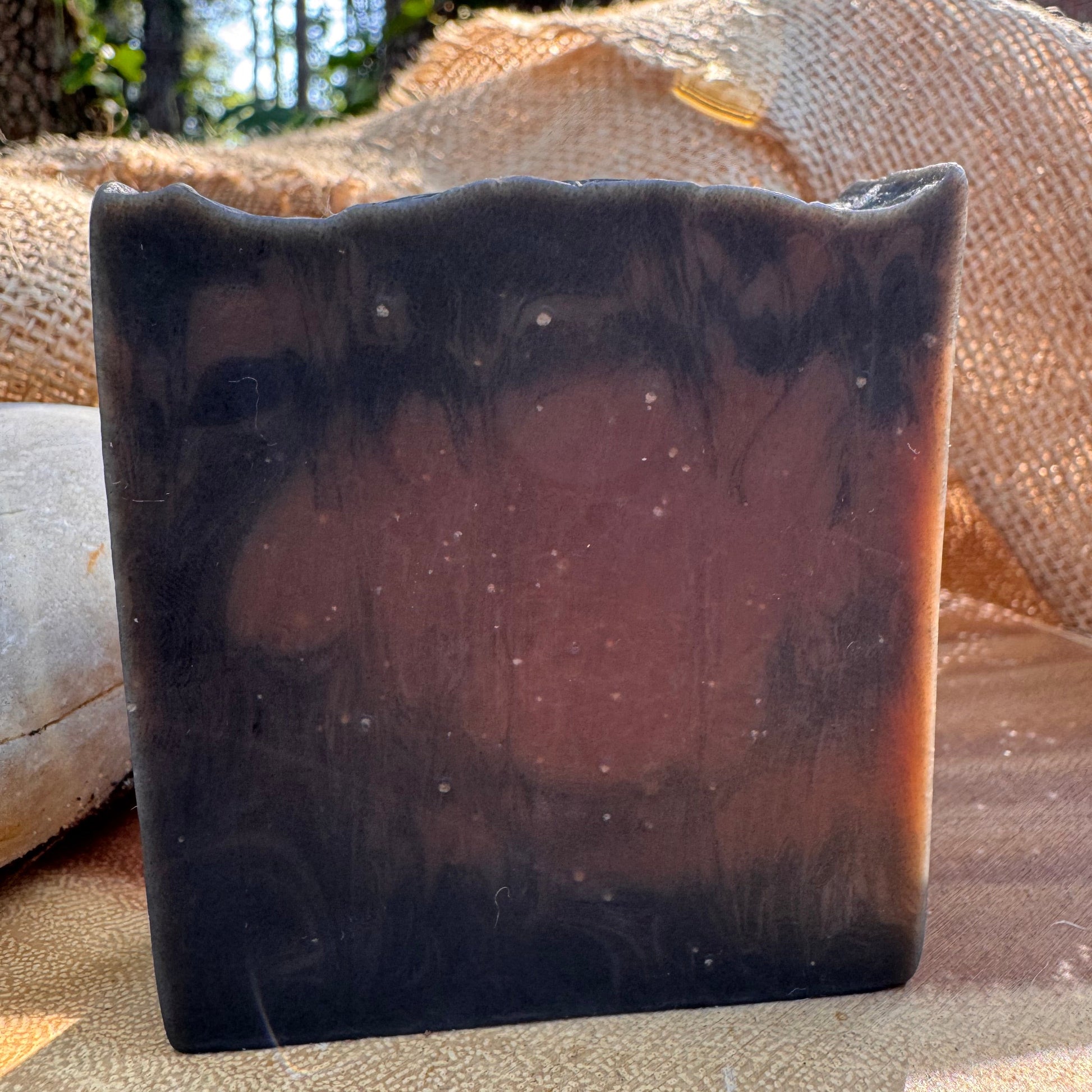 Dark brown soap bar against a textured beige background