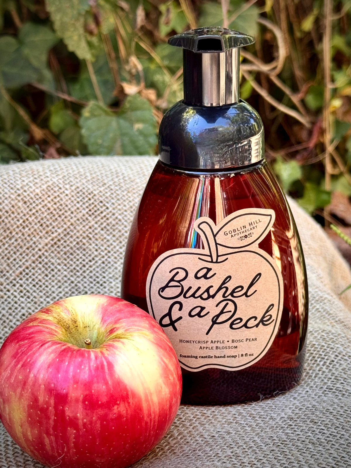 amber bottle of foaming hand soap next to an apple