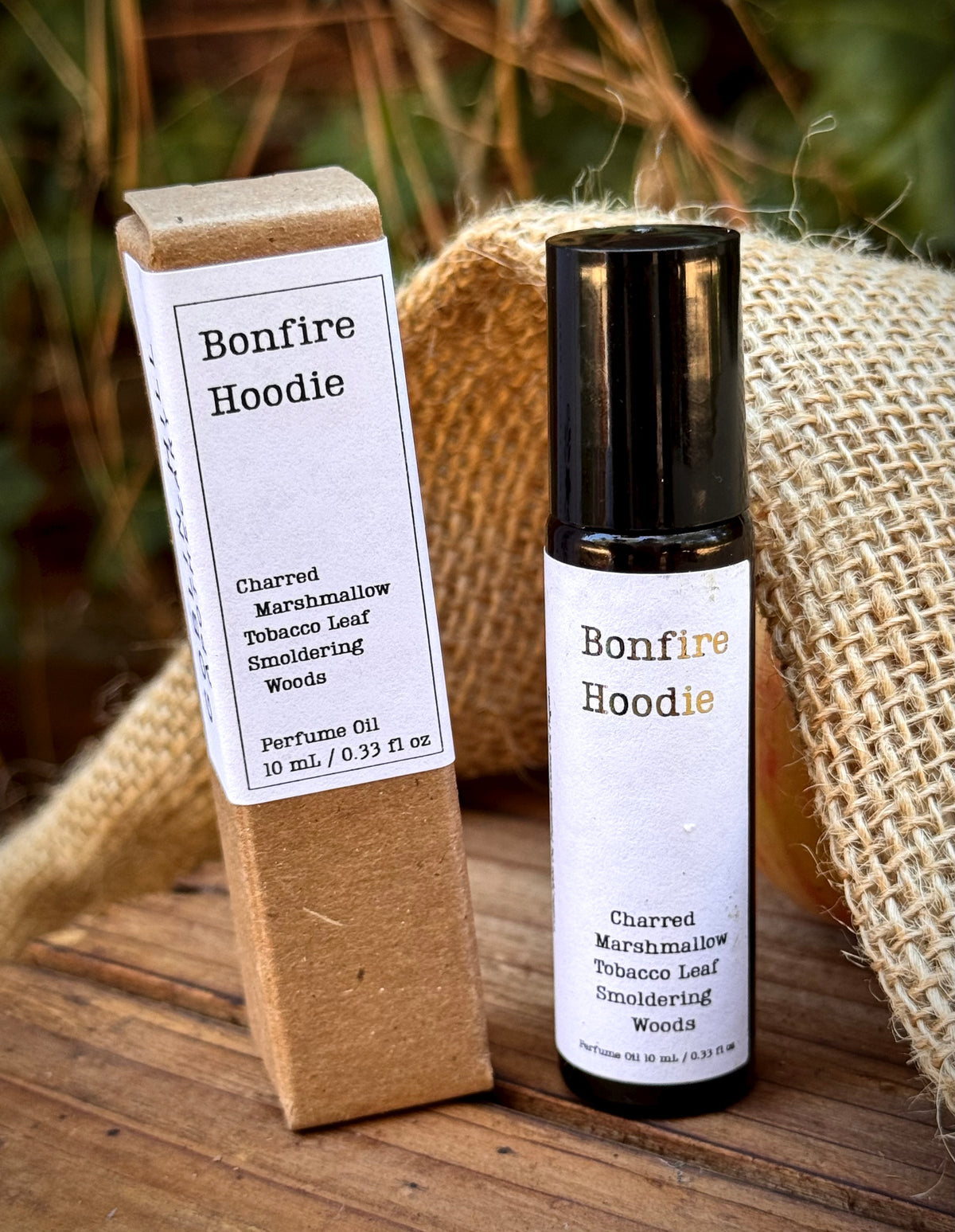 perfume roller bottle next to a brown box with a white label that reads bonfire hoodie