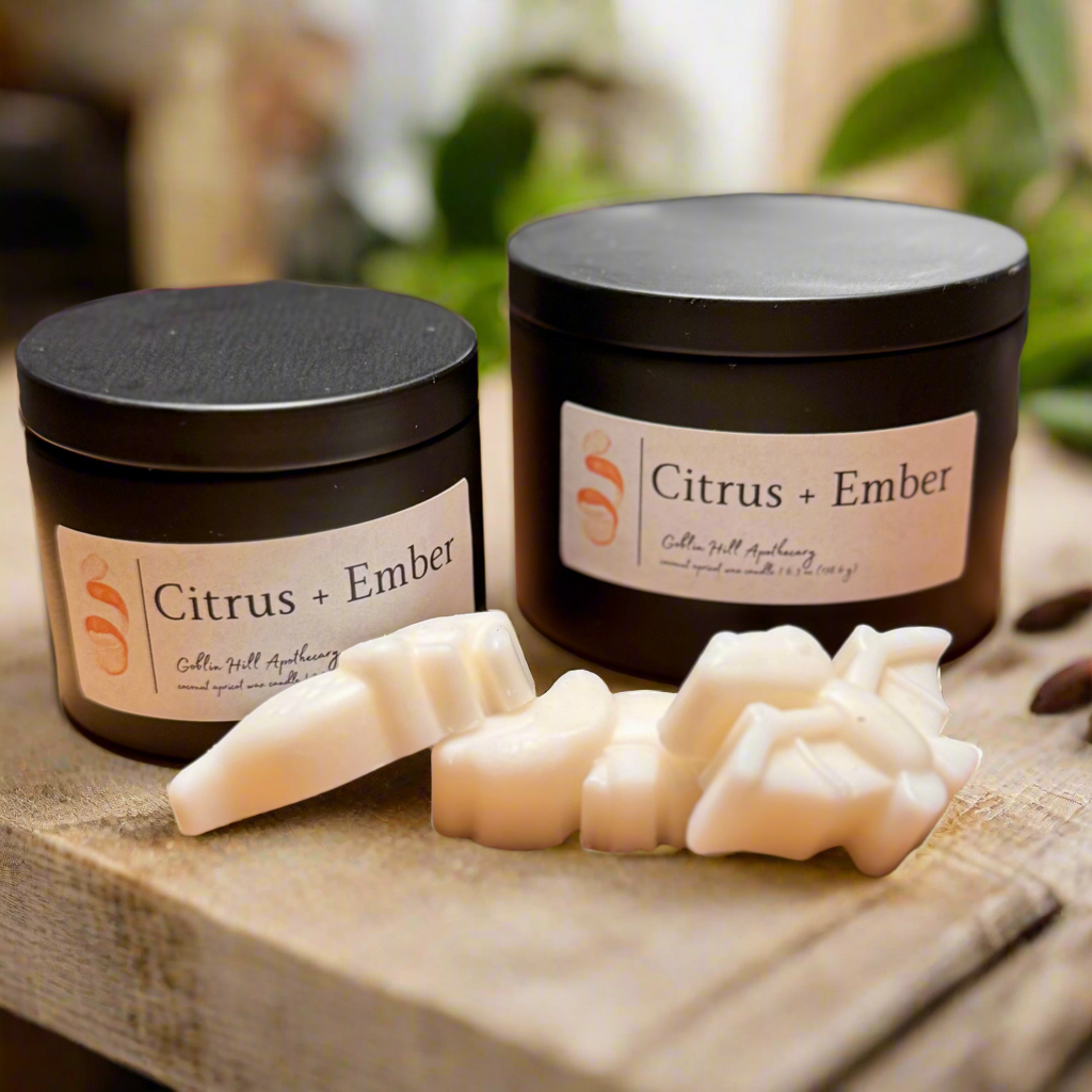 Two black jars labeled 'Citrus + Ember' with soap on a wooden surface.