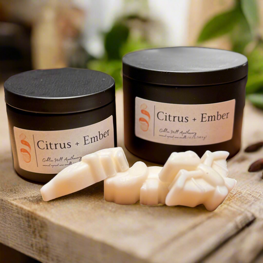 Two black jars labeled 'Citrus + Ember' with soap on a wooden surface.