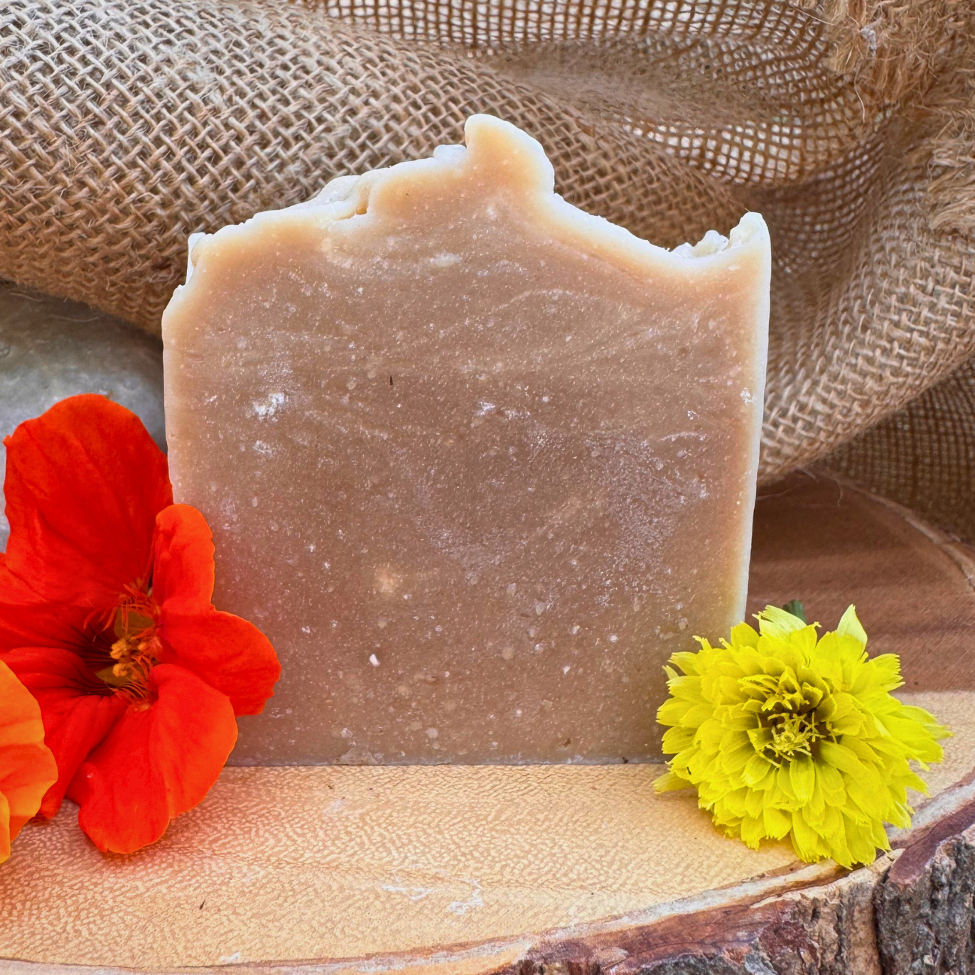 Bar of soap with a red and yellow flower on a wooden surface