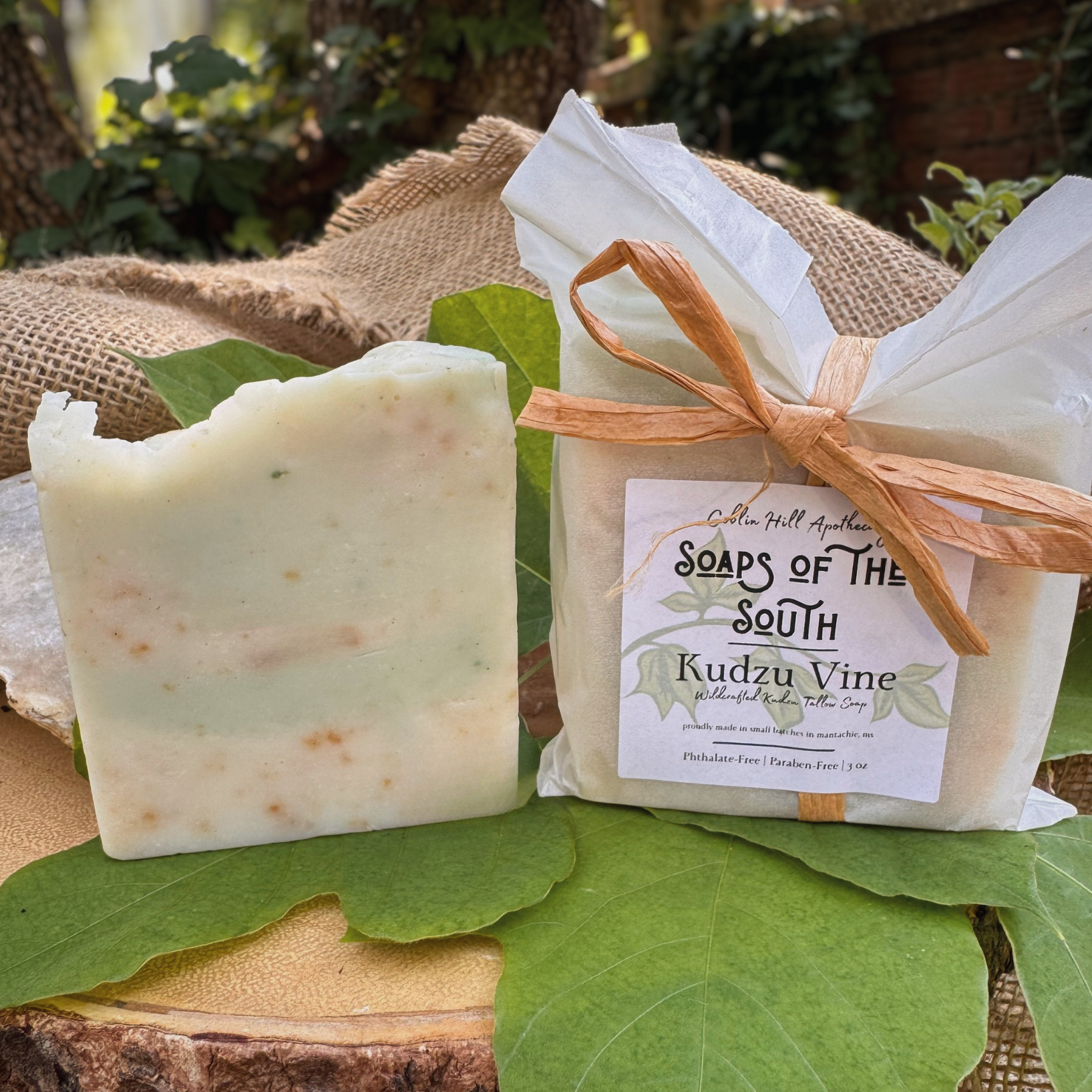 Bar of soap and wrapped soap on green leaves with a natural background