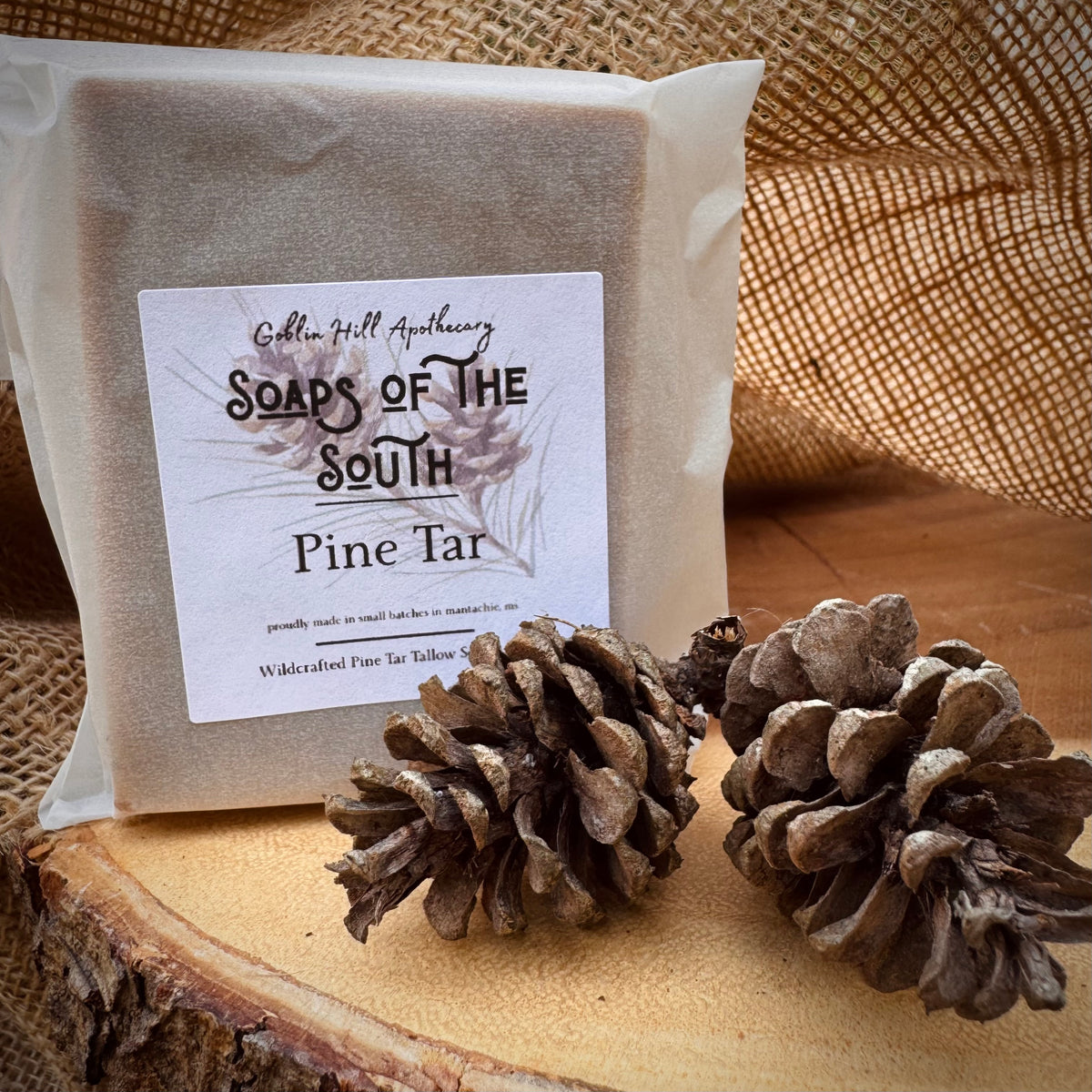 Pine tar soap with packaging and pine cones on a wooden surface